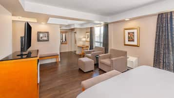 Una camera d'albergo con un letto, una scrivania, una sedia, un divano, una TV e un quadro appeso al muro.