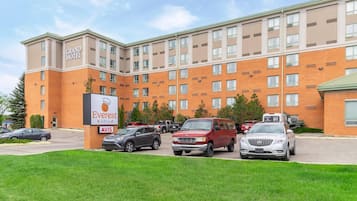 Et flereetagers hotel med facade af mursten, et skilt for Everest Grill og en parkeringsplads med flere biler.