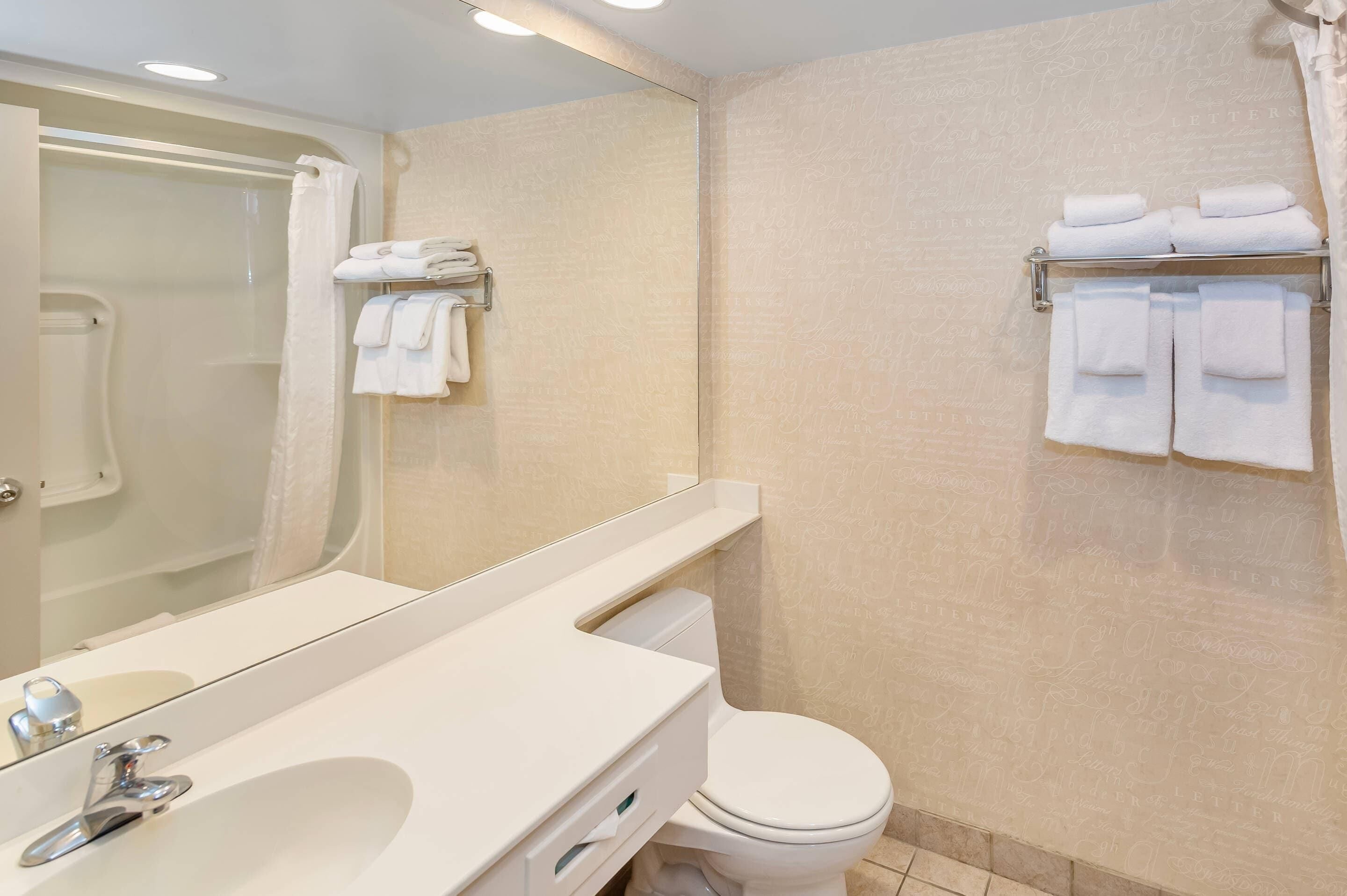 A bathroom with a shower, toilet, and a towel rack with folded towels.