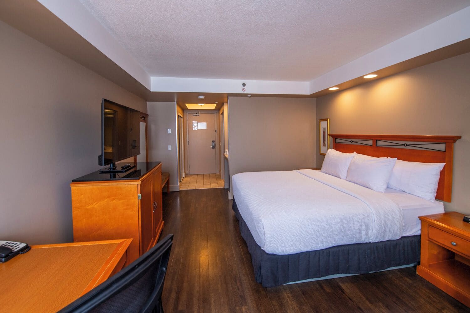 A hotel room with a bed, a TV, a desk, and a wardrobe.
