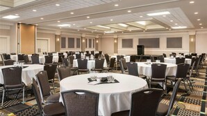 A conference room with round tables, chairs, and a stage. - Grand Hotel & Conference Centre Calgary Airport, an Ascend Collection Hotel (Calgary)
