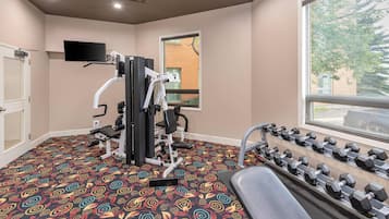 Un gimnasio con equipo de ejercicio, un televisor y una ventana con vistas al exterior.