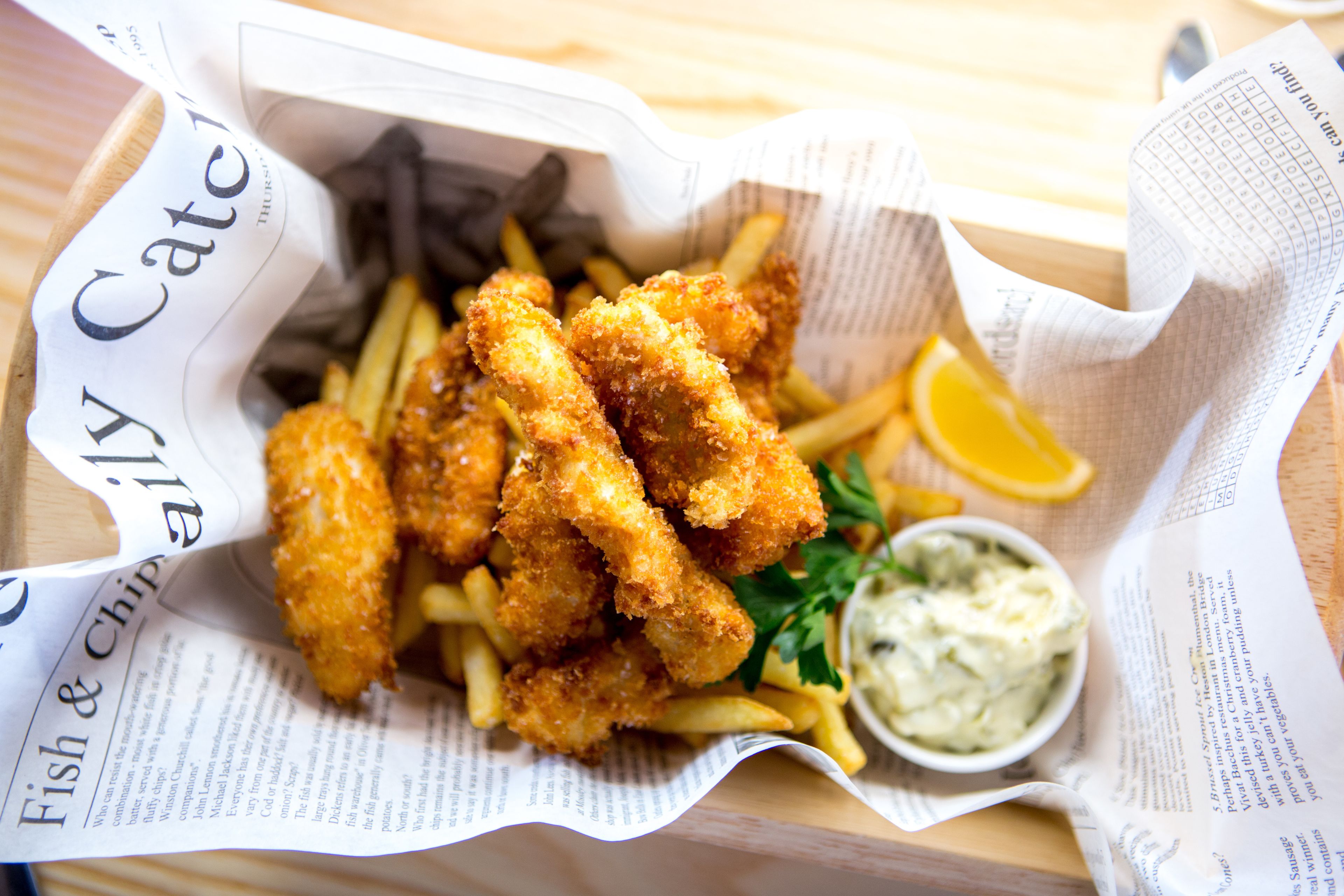 Ein Gericht mit paniertem Fisch, Pommes und Remoulade.