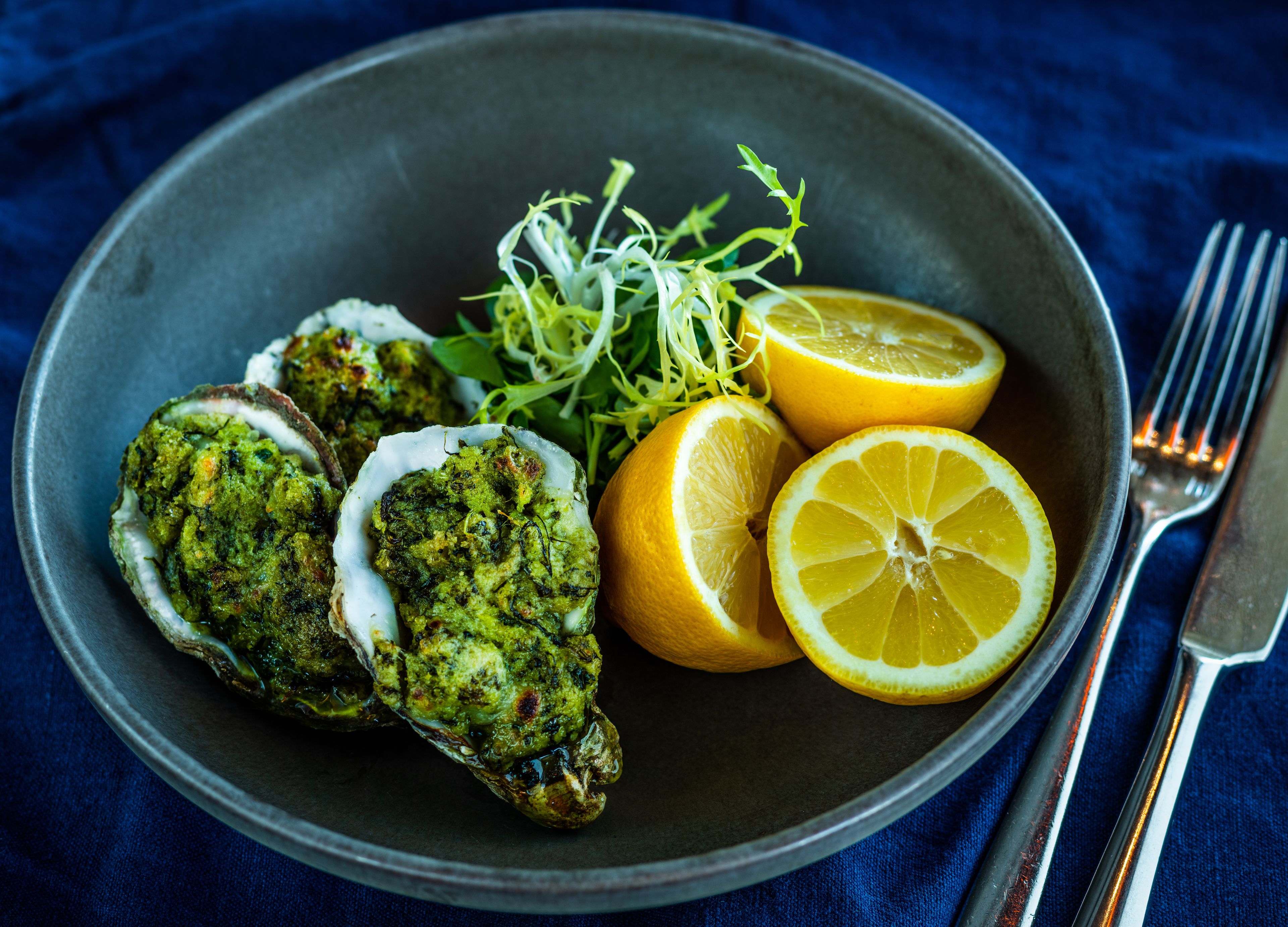 Un plato con ostras, rodajas de limón y verduras.