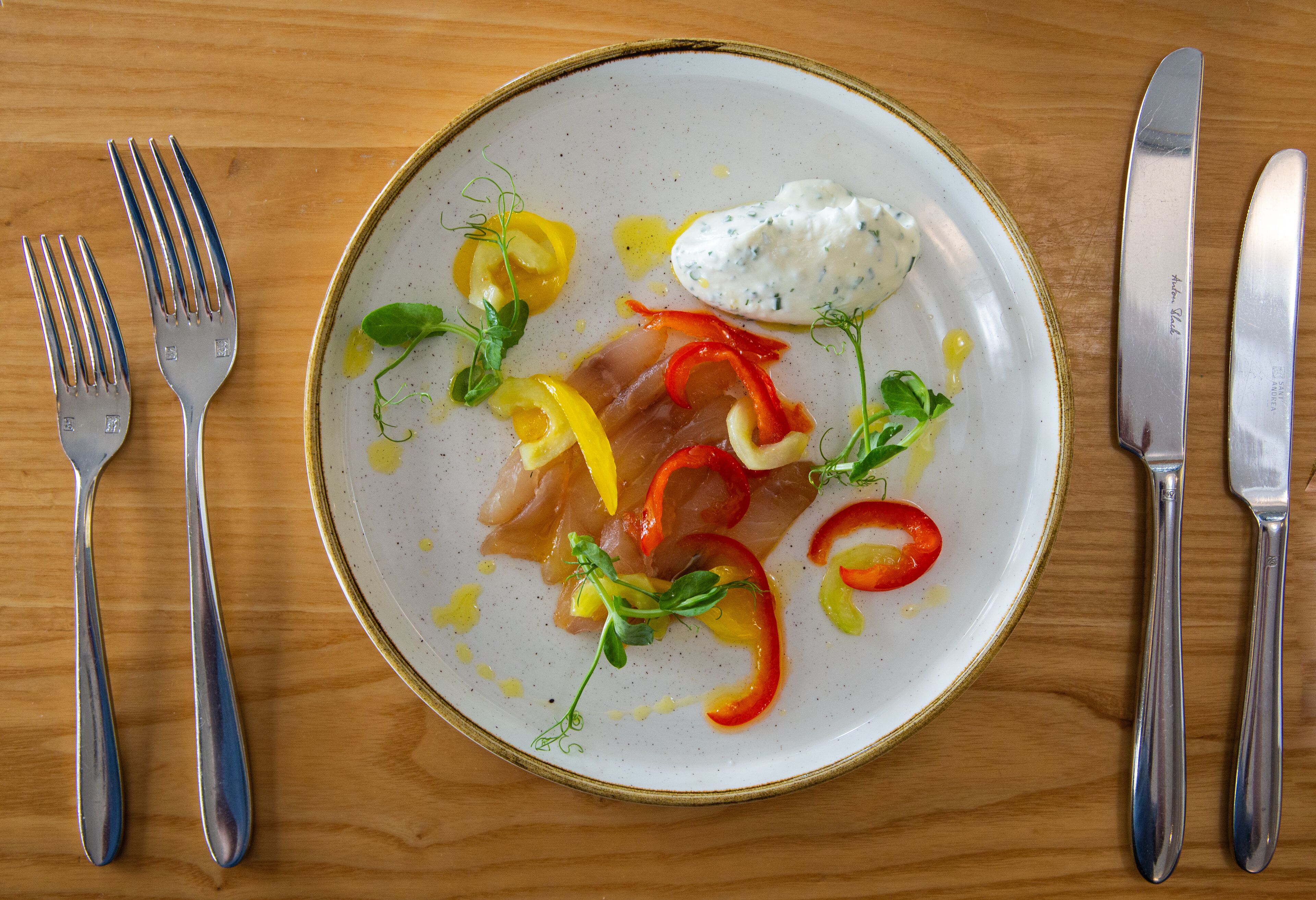 A plate of food with a fork and knife on a wooden table.