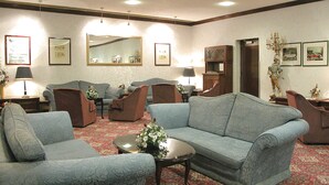 A spacious living room with a large blue sofa, two armchairs, a coffee table, and a patterned carpet. - Britannia Coventry Hill Hotel (Coventry)