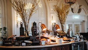 Una barra de desayuno luminosa y elegante, con candelabro, plantas decorativas y diversas opciones para el desayuno.