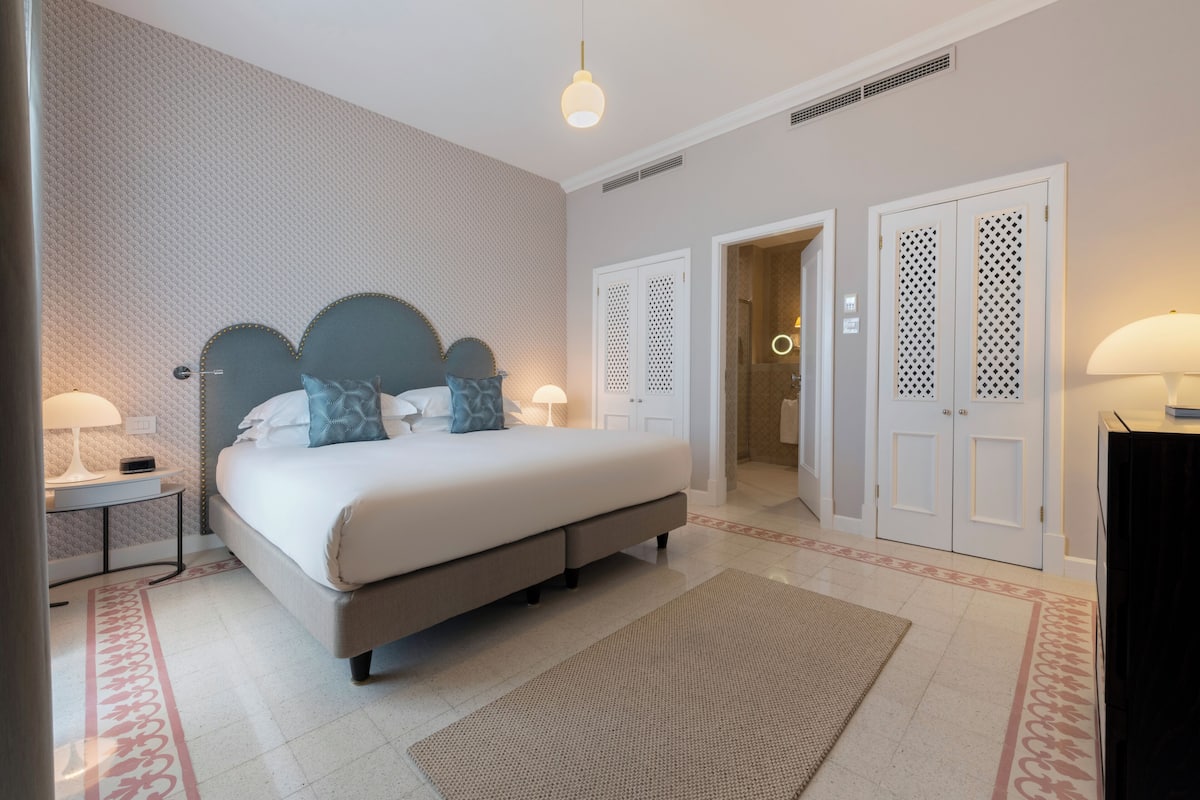 A bedroom with a bed, nightstands, a rug, and a wardrobe.