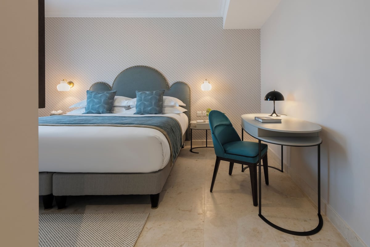 A neatly arranged bedroom with a bed, bedside tables, a chair, and a small table.