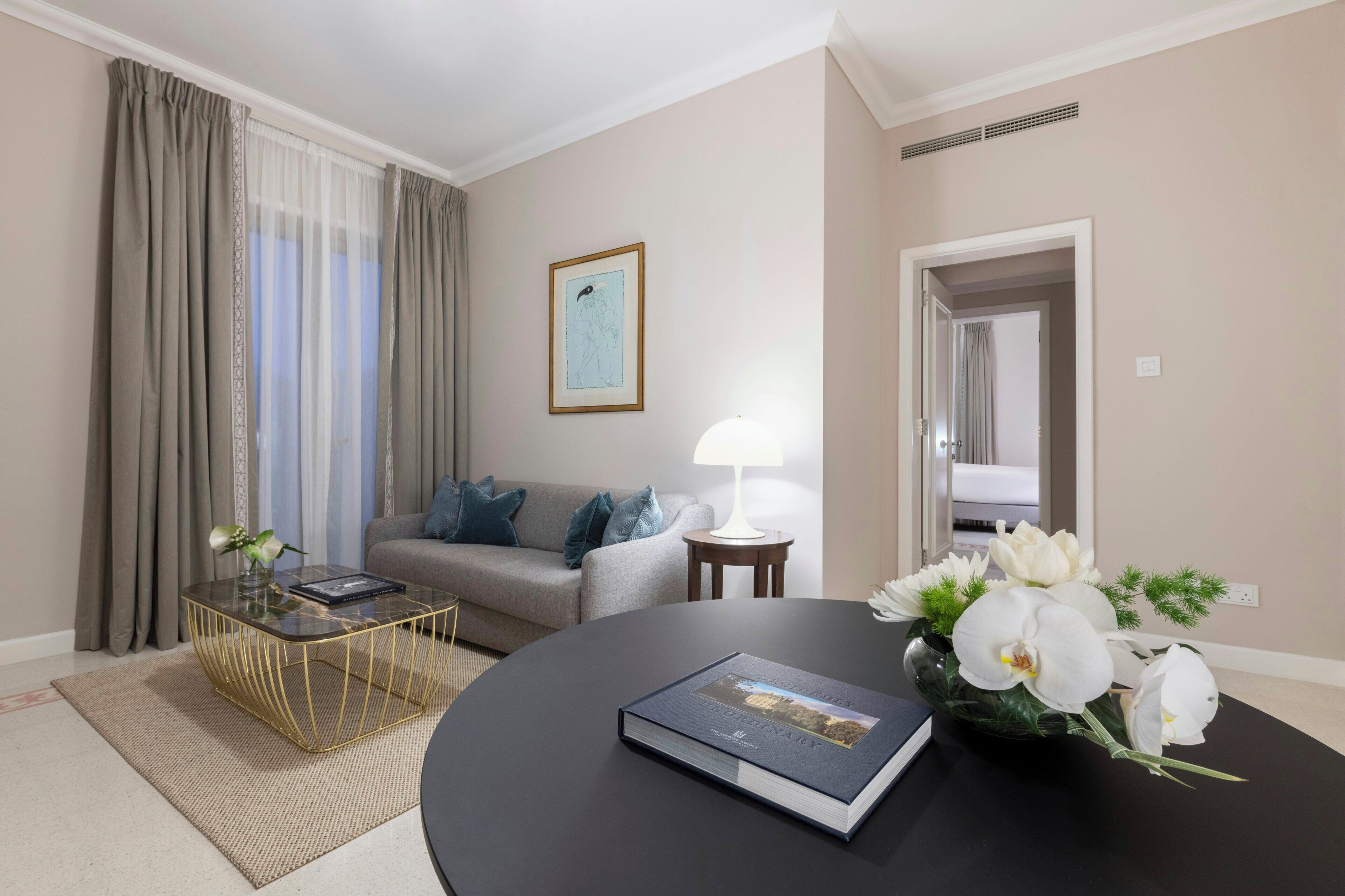 A modern living room with a sofa, a coffee table, a lamp, and a vase of flowers.