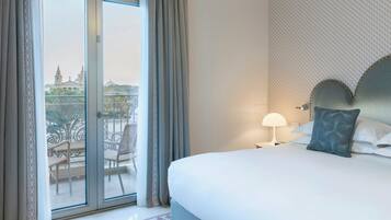 Habitación de hotel con cama, mesita de noche, lámpara, vista a un balcón con sillas y una pared con diseño.