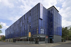 Un bâtiment moderne doté d’une façade bleue verticale, d’un restaurant de cuisine turque et d’un hôtel Travelodge.