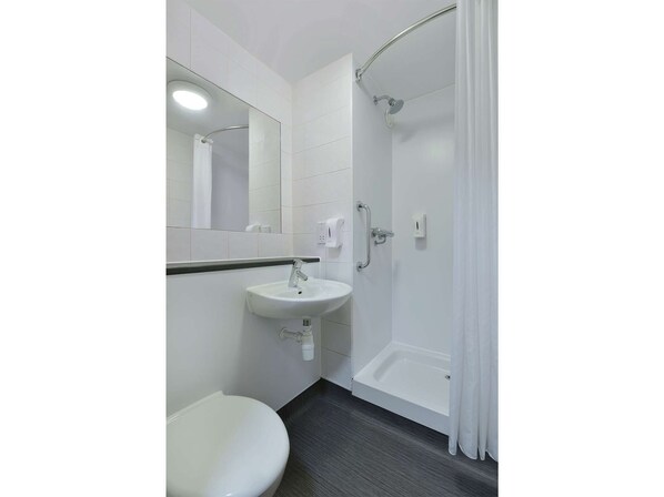 Ein modernes Badezimmer mit Waschbecken, Toilette und Dusche, alles in Weiß.