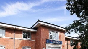 A Travelodge hotel with a brick facade, a well-maintained lawn, and a clear sky. - Travelodge Stonehouse (Stonehouse)