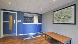 Un espace d’accueil avec un mur bleu, un banc et une carte encadrée accrochée au mur.
