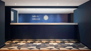 A reception area with a blue wall, a clock, and a 'hello & welcome' sign. - Travelodge Edinburgh Central (Edinburgh)