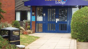 La entrada a Redwings Lodge con un toldo azul, un contenedor de basura y un cartel.