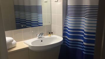 Ein Badezimmer mit einem weißen Waschbecken, einer Toilette, einem Spiegel und einer Duschvorhang mit blauen Streifen.