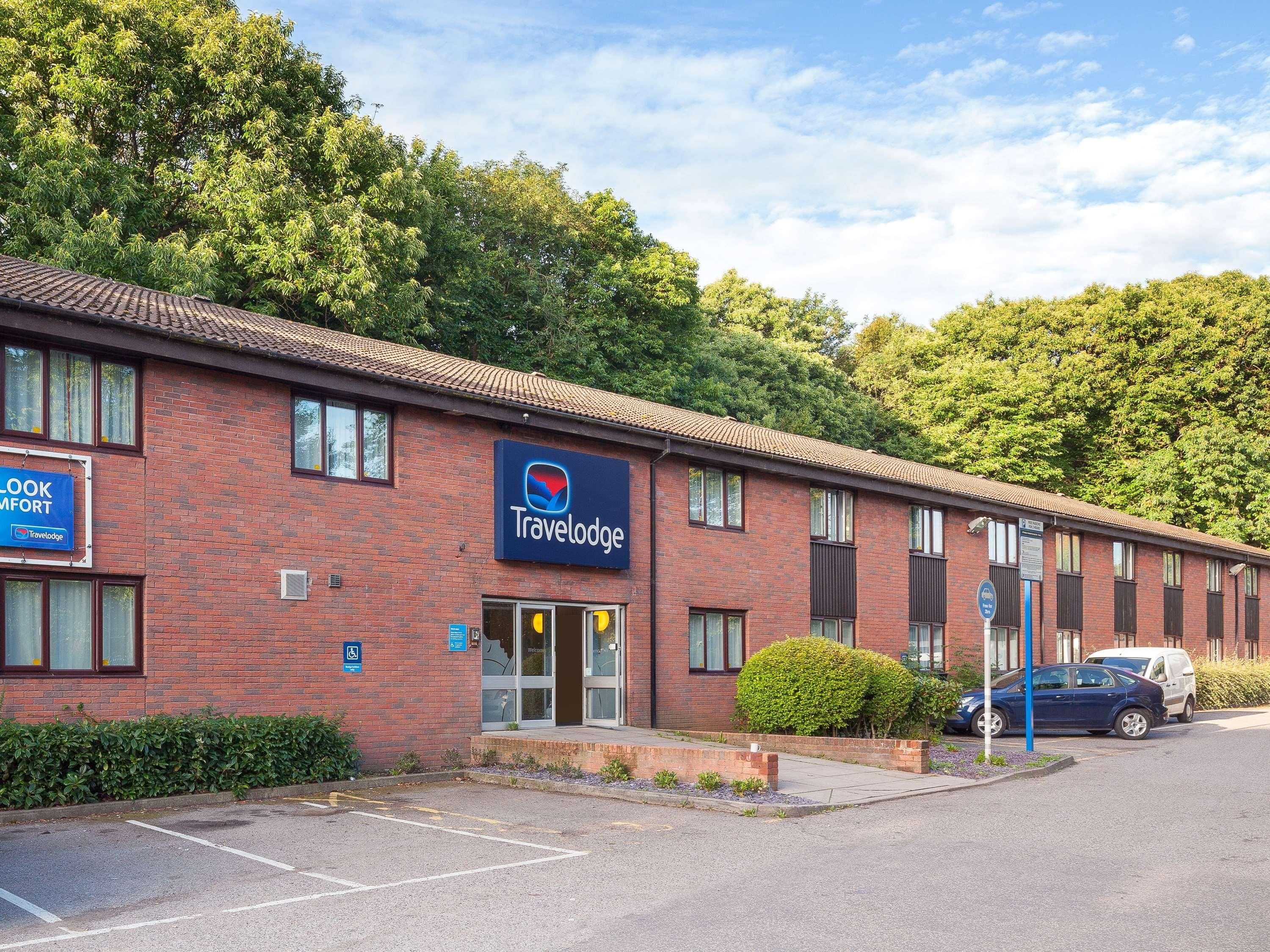 A Travelodge hotel with a brick facade, a visible entrance, and a parking area.