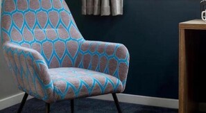 A chair with a geometric pattern, a dark wall, and a small wooden table. - Travelodge Barnsley (Barnsley)