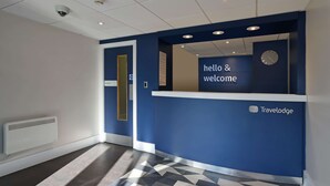 Un espace d’accueil avec un mur bleu, une horloge et une pancarte indiquant « Bonjour et bienvenue ».