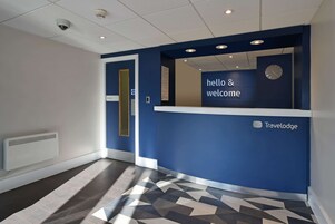 Un área de recepción con pared azul, un reloj y un letrero que dice 'hello & welcome'.