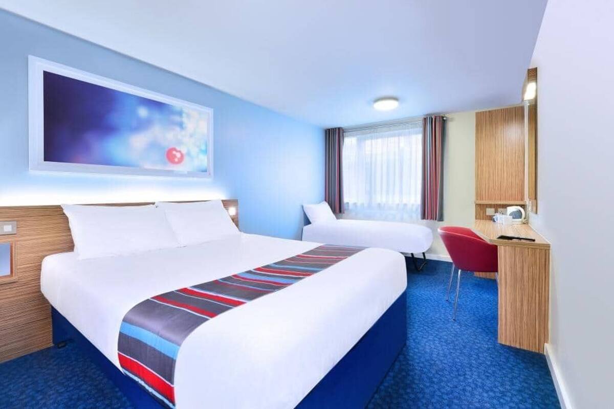Une chambre d’hôtel avec un grand lit, un bureau et une chaise.