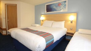 Ett hotellrum med en stor säng, två sängbord med lampor, en dörr och ett konstverk som hänger på väggen.