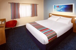 A hotel room with a bed, a desk, a chair, and a window with curtains. - Travelodge Kettering Thrapston (Kettering)