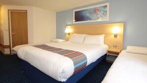 A hotel room with a large bed, two bedside tables, a headboard with wall-mounted lamps, and a door.