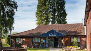 A Travelodge hotel with a brick facade, a red-tiled roof, and a well-maintained lawn.