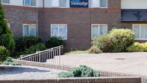 A Tavelodge hotel with a brick facade, multiple windows, and a paved courtyard. - Travelodge Saltash (Saltash)