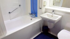 A bathroom with a white bathtub, a sink, and a toilet. - Travelodge Saltash (Saltash)
