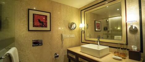 A bathroom with a white sink, a large mirror, a framed picture on the wall, and a toilet.