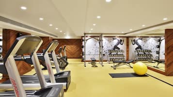 A gym with treadmills, weight machines, and a yellow exercise ball.
