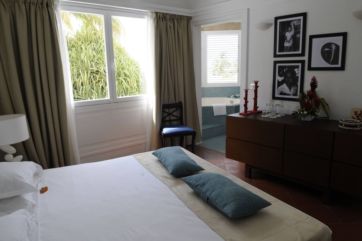 A hotel room with a bed, a chair, a dresser, and a window with curtains.