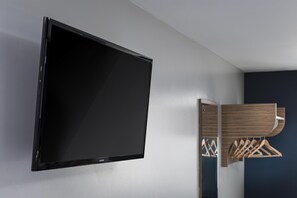Ein flachbildfernseher an der Wand, ein hölzerner Kleiderständer und ein Spiegel.