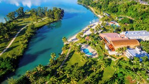 An aerial view of a resort with a swimming pool, beach, and lush greenery. - Holiday Inn Resort Vanuatu by IHG (Port Vila)