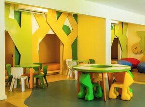 A colorful children's play area with a green and yellow playhouse, multiple seating areas, and a round table with papers. - Holiday Inn Resort Vanuatu by IHG (Port Vila)