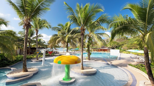 A resort pool area with palm trees, a water feature, and lounge chairs. - Holiday Inn Resort Vanuatu by IHG (Port Vila)