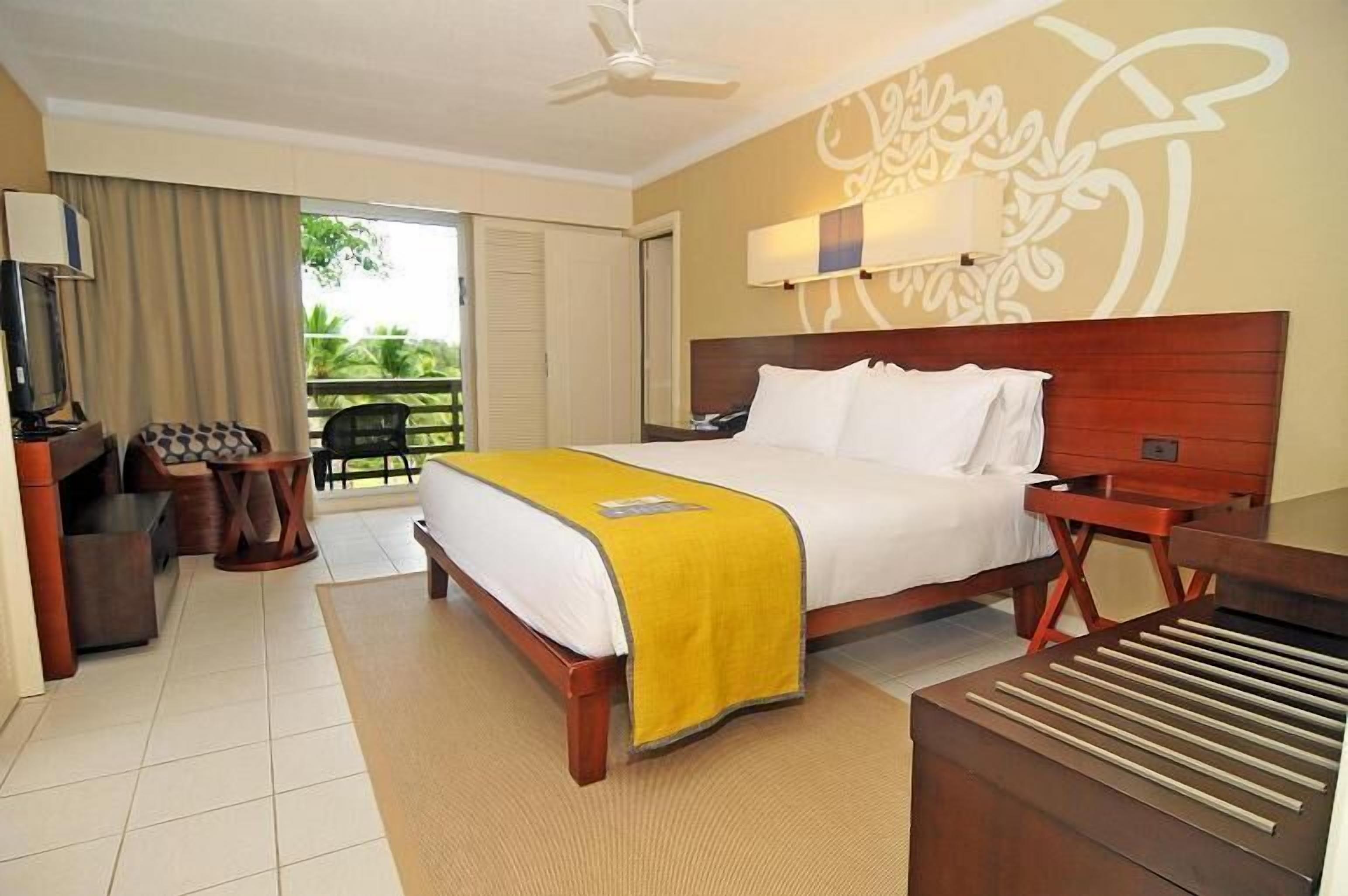 Una habitación de hotel con cama, televisión, escritorio y silla.