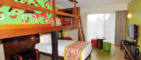 Habitación de hotel con literas, un escritorio con computadora, televisión y un amplio ventanal con cortinas.