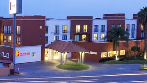 A hotel with a modern design, featuring a central courtyard with a covered seating area.