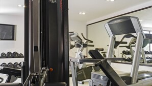 A gym with various exercise equipment, including dumbbells and a treadmill.