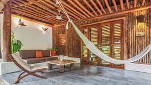 A cozy room with a hammock, wooden ceiling, and a sofa with cushions. - The Explorean Selva Maya Kohunlich (Kohunlich)