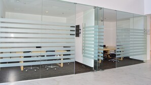 Ein moderner Arbeitsbereich mit Glastrennwänden, Bürostühlen und einem sichtbaren Schreibtischbereich.