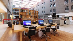 Ein moderner Arbeitsraum mit einem langen Holztisch, vier schwarzen Bürostühlen und mehreren Computermonitoren.