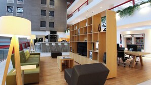 Ein modernes Interieur mit einer Couch, einem schwarzen Sessel, einem Holzregal und einem Fernseher.