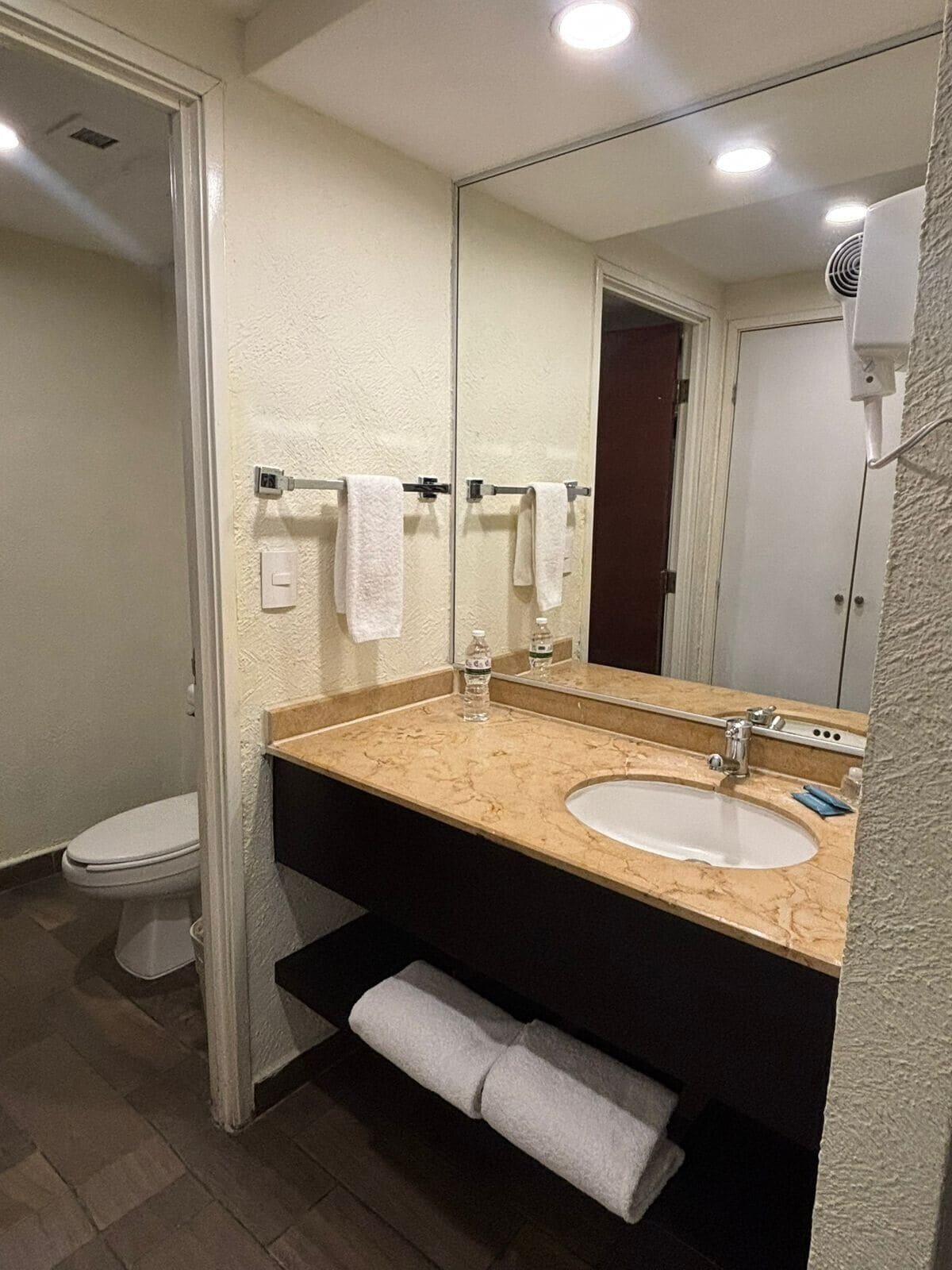 Un baño con lavamanos, espejo, toallero y retrete.