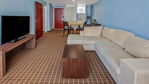 A modern living room with a flat-screen TV, a wooden coffee table, a beige sofa, and a patterned carpet. - CHN Hotel Monterrey Centro, Trademark by Wyndham (Monterrey)